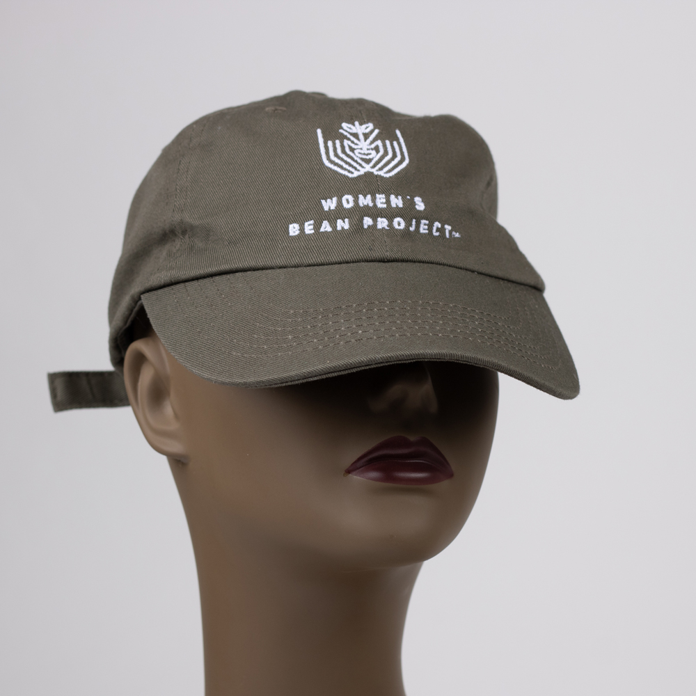 A close up of a sage green baseball hat embroidered with the Women's Bean Project logo in white.